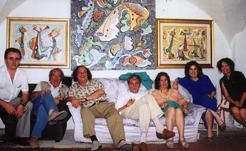 Victor Bussoletti (3rd from left) and friends, with Bussoletti's paintings (behind). Photo: Bill Newman