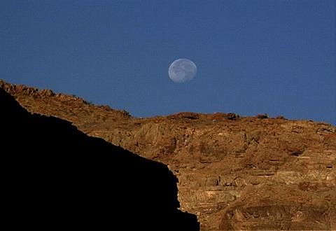 A still frame of the moon and desert cliffs. Photo © Video Arts International