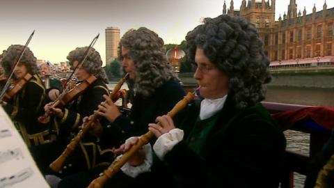 A still from the performance, angle/view 3 selected, showing members of the English Concert playing on a reconstructed barge on the modern River Thames. © 2003 BBC Worldwide Ltd/Opus Arte